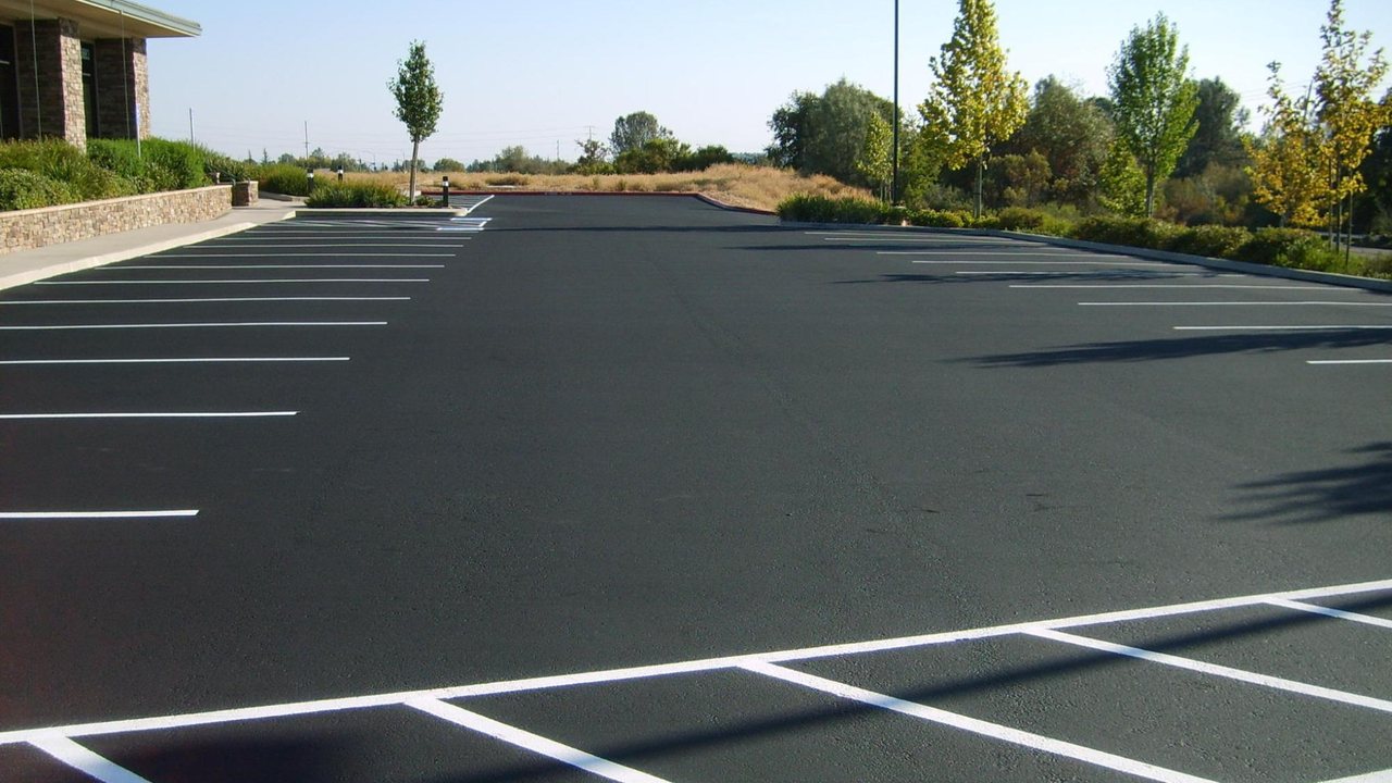A freshly paved and striped commercial parking lot beside an office building